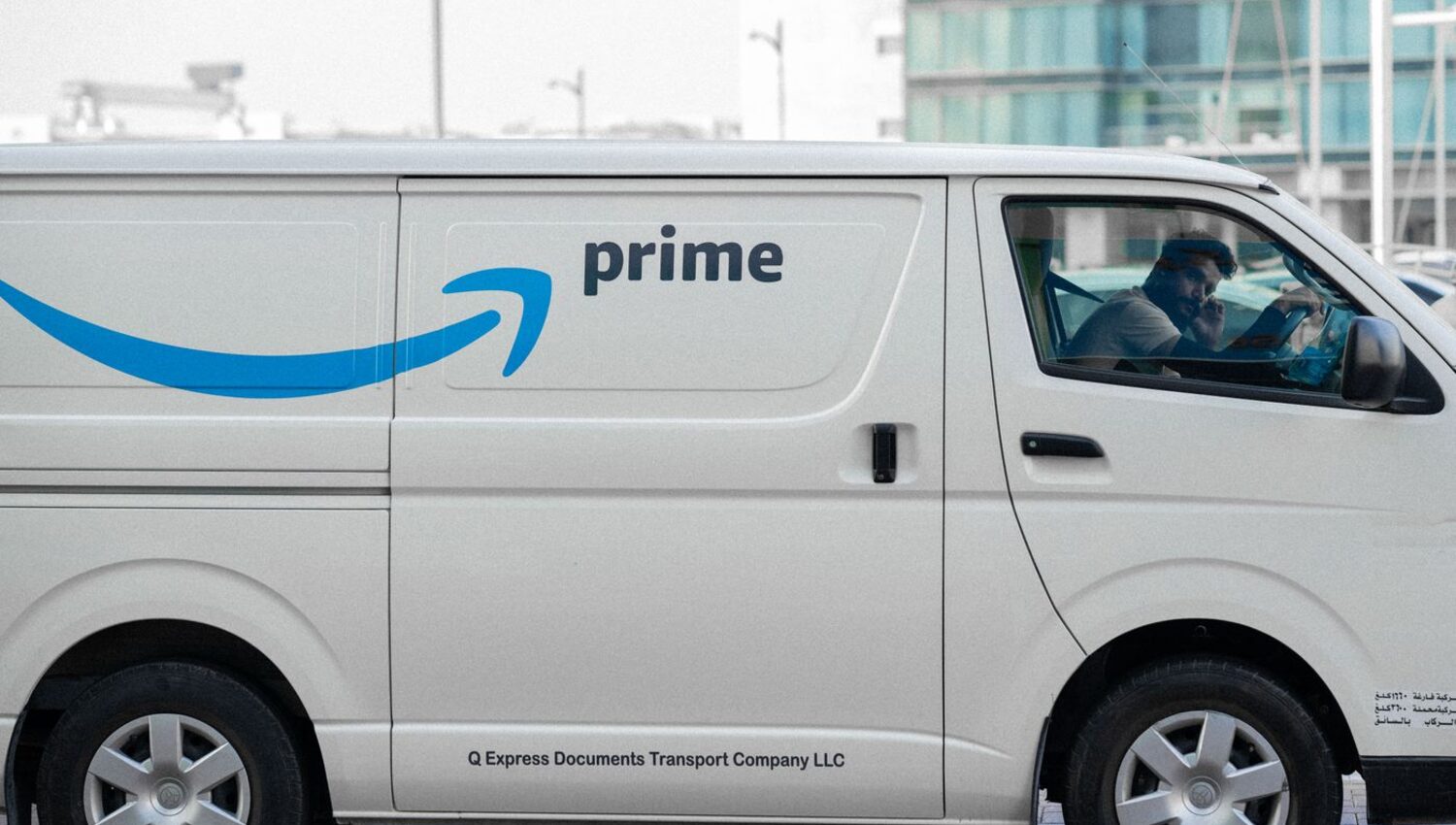 Amazon-style delivery van moving through a U.S. city street on route
